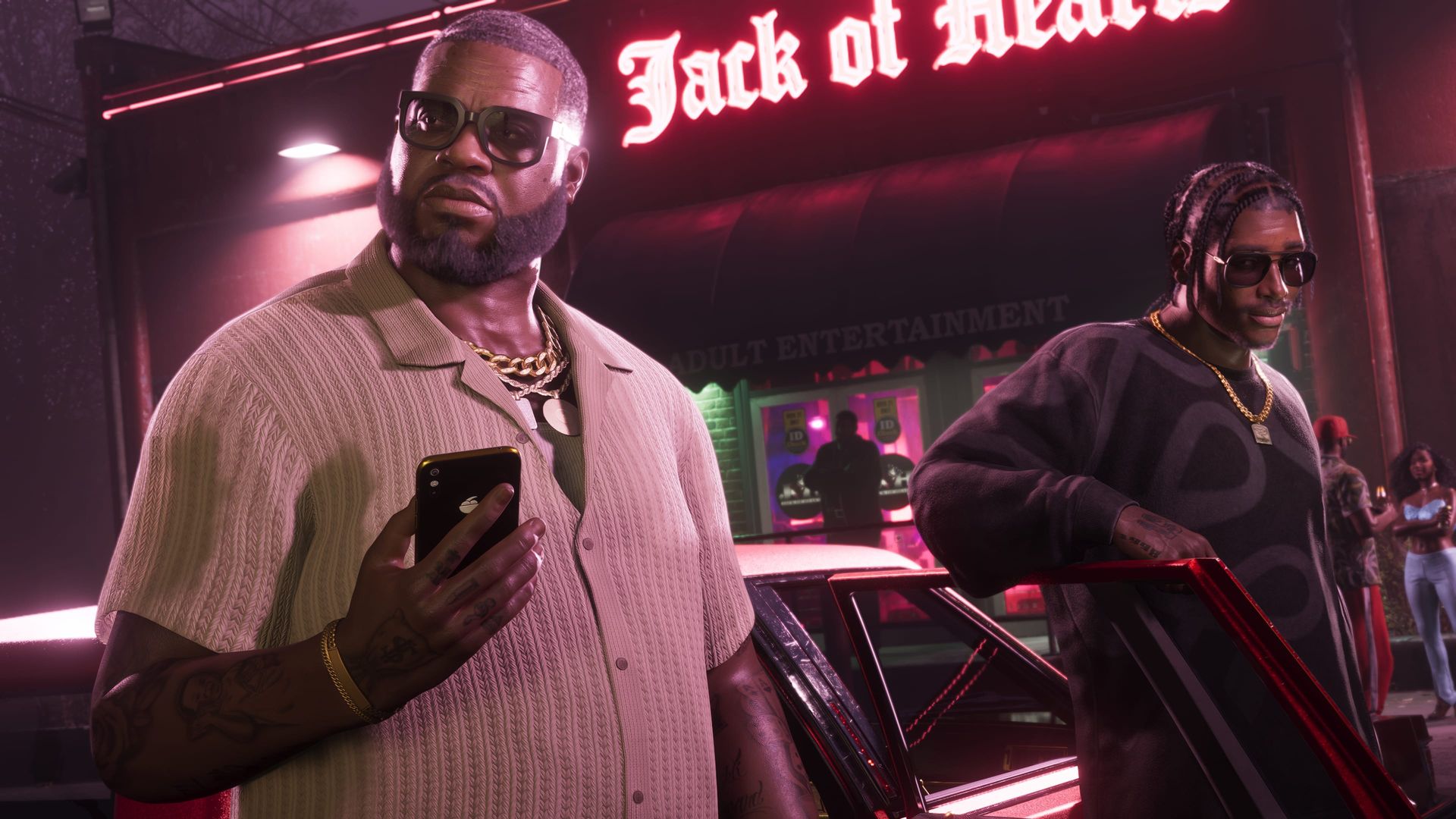 Boobie Ike schaut vor dem Jack of Hearts auf sein Handy, dahinter leuchtet das Neonschild