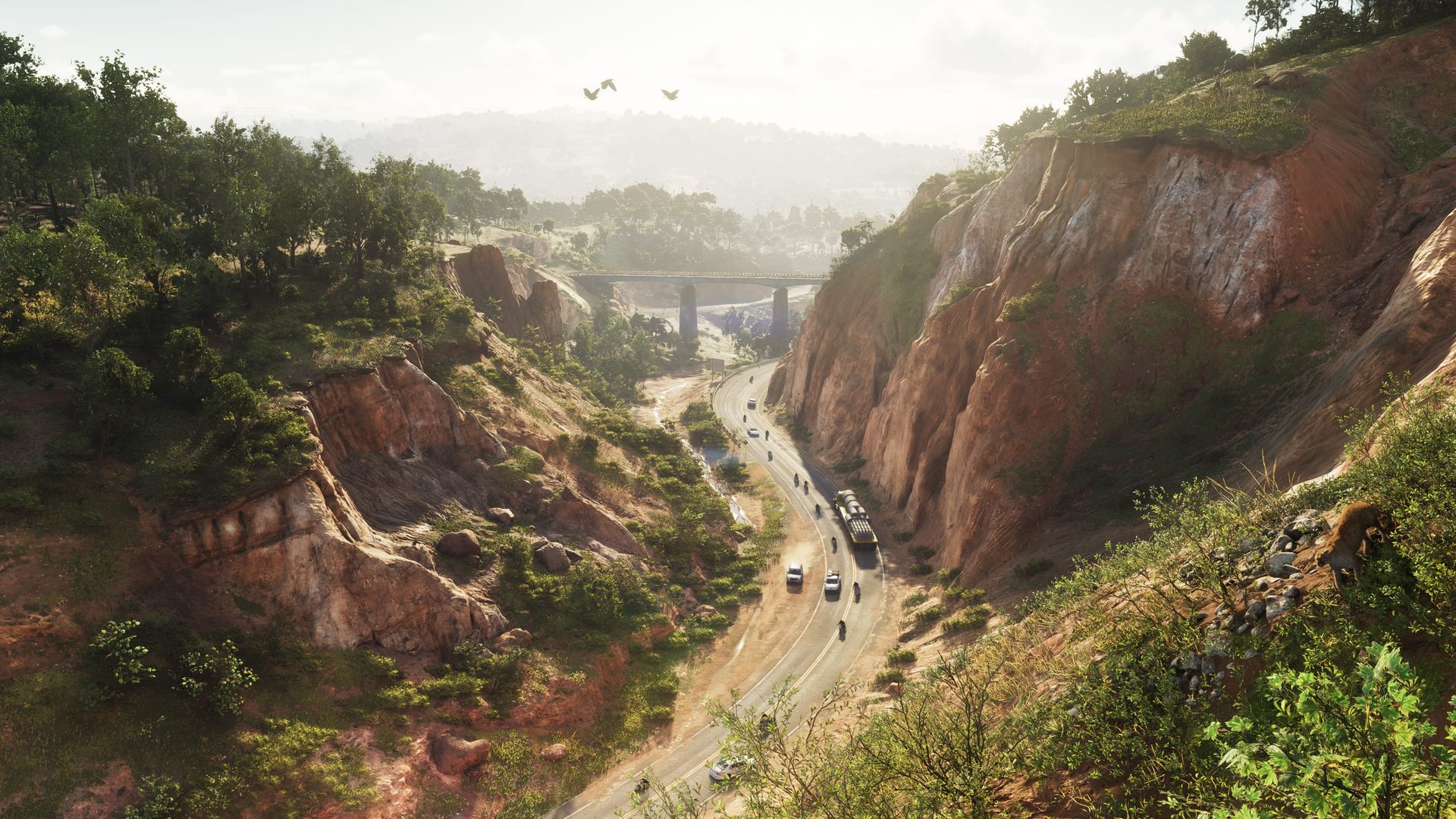 A highway cuts through a red-rock canyon between forested hills